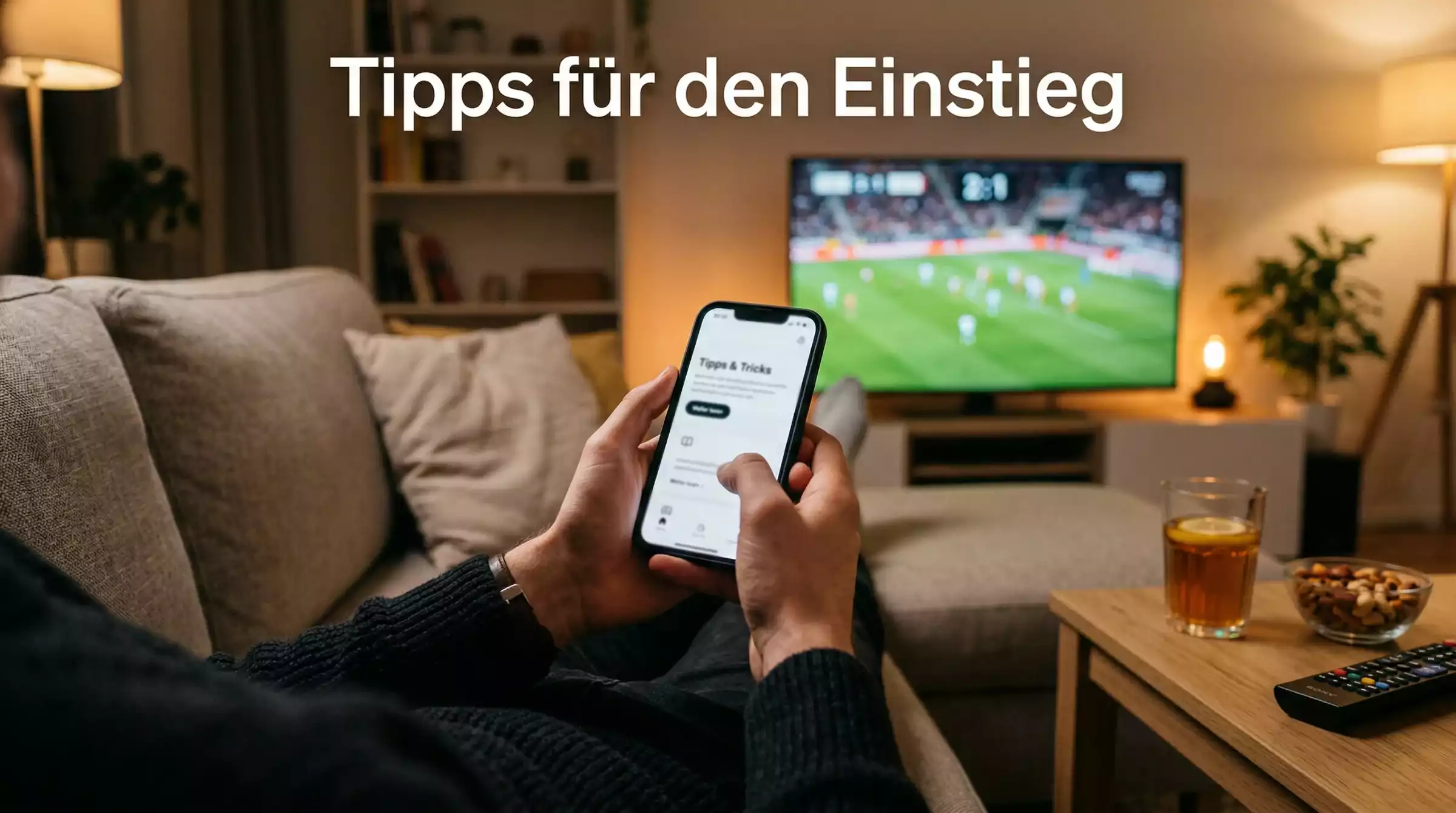 Person entspannt auf dem Sofa mit Smartphone und Fernseher der ein Fussballspiel zeigt
